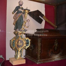 Horní část postavníku s plastikou patrona cechu a cechovní truhlice. Foto: Kamila Dvořáková