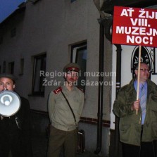 Čelo průvodu - řečník s tlampačem, dohlížející příslušník SNB a tajný s transparentem. Foto: Kamila Dvořáková
